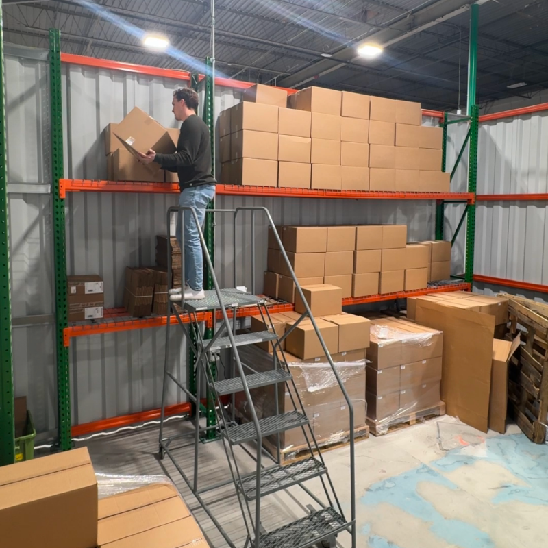 Drew stocking boxes on warehouse shelves