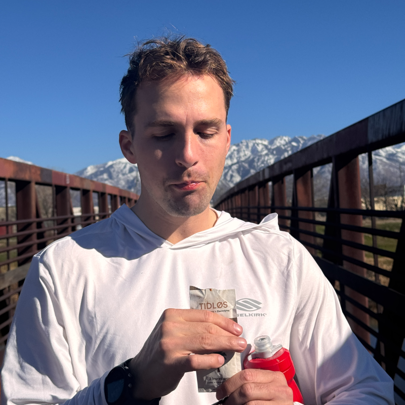 Drew outdoors holding a TIDLØS energy gel after training